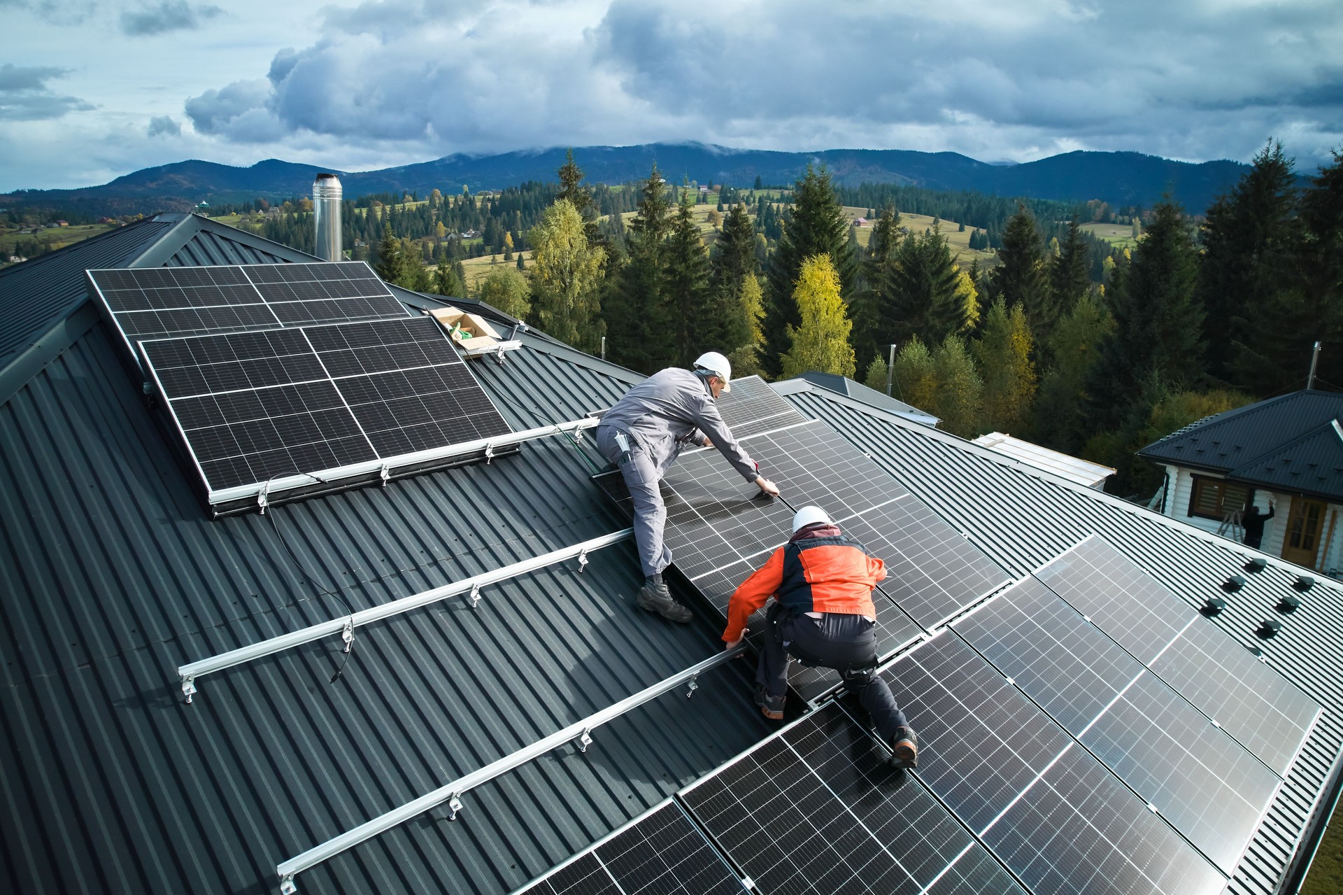 Men workers installing solar panels on roof of house.